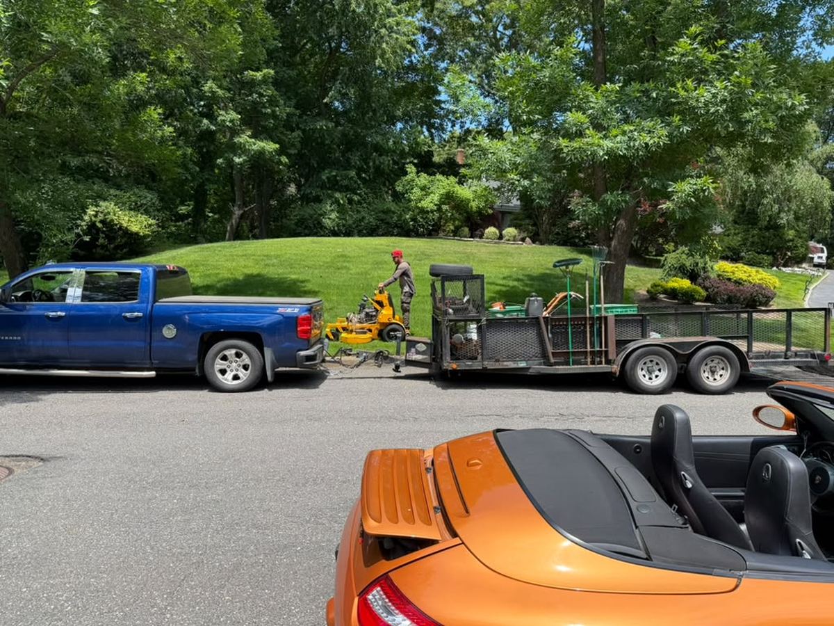New Century Suffolk truck, trailer and mowers parked at a job site on Long Island