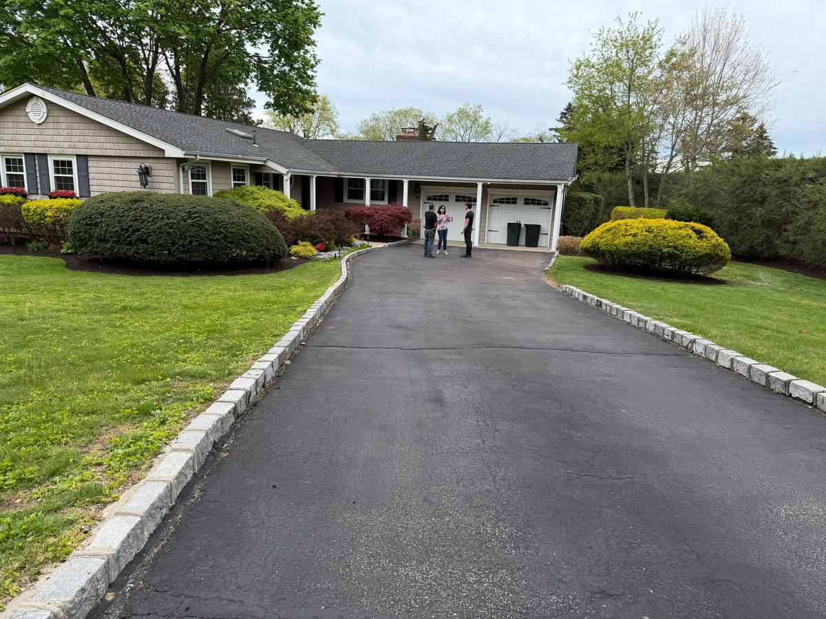 Sealed driveway framed by rounded shrubs and a maintained lawn